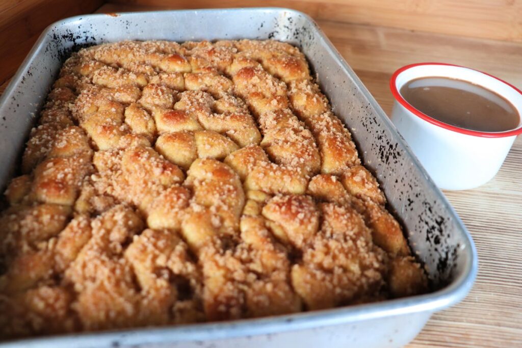 An entire pan of coffee cake sits on a counter next to a mug of coffee.